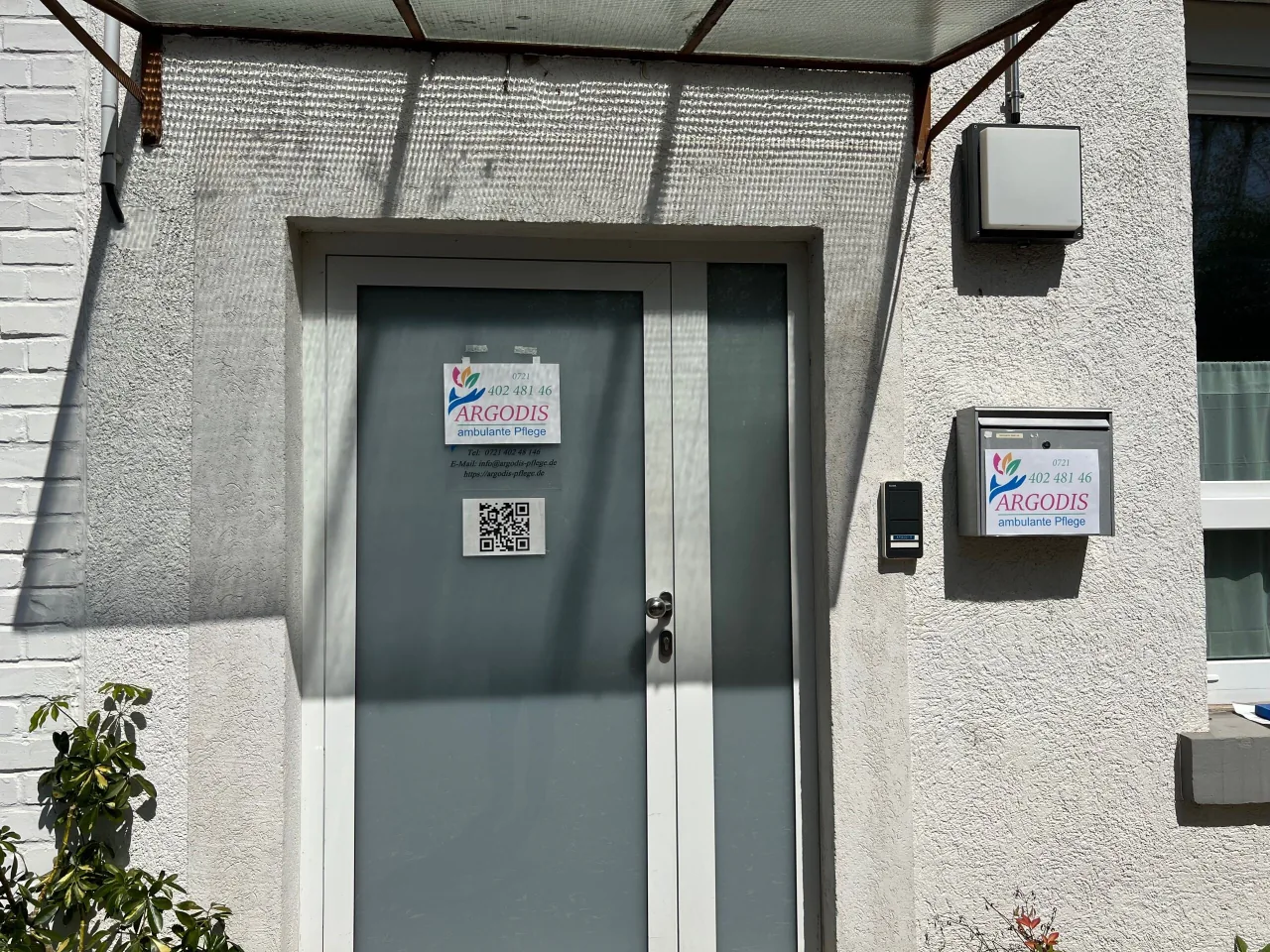 Eingang zu Argodis Pflege mit Firmenschild und Türklingel
